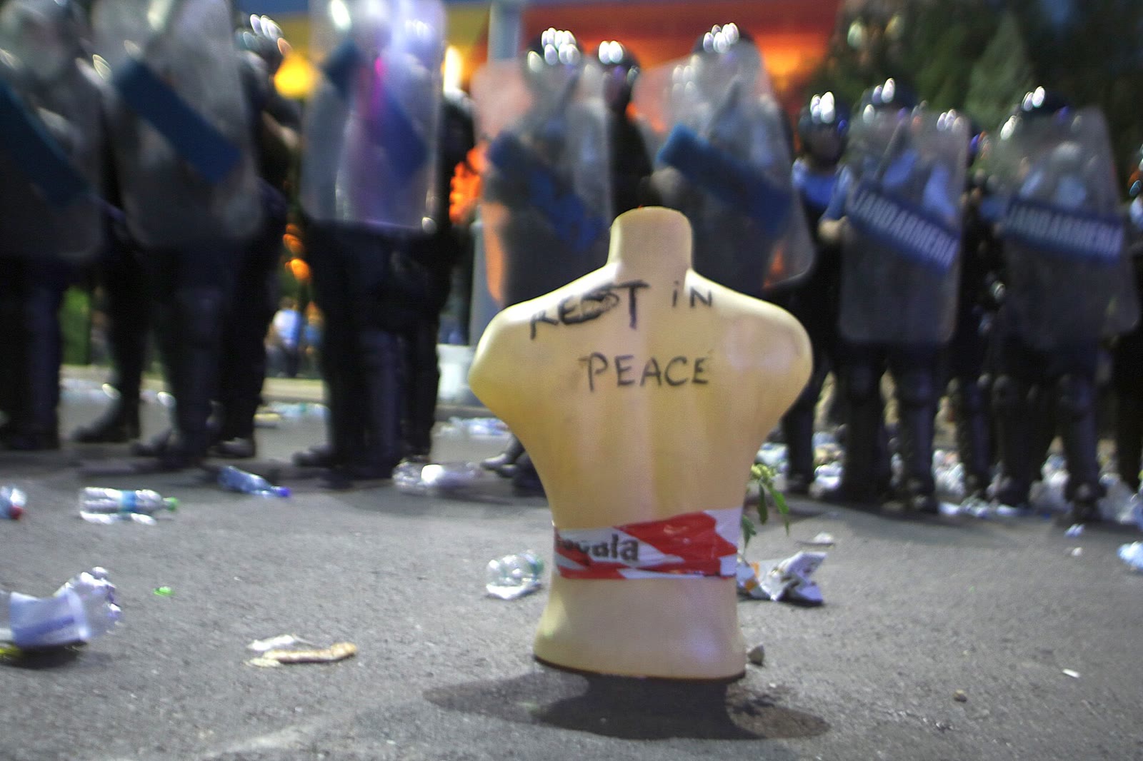 Un manechin cu mesajul Rest in peace în fața unui cordon de jandarmi la protestul din 10 august 2018